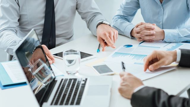 Reunión de trabajo con un portátil y gráficos sobre la mesa